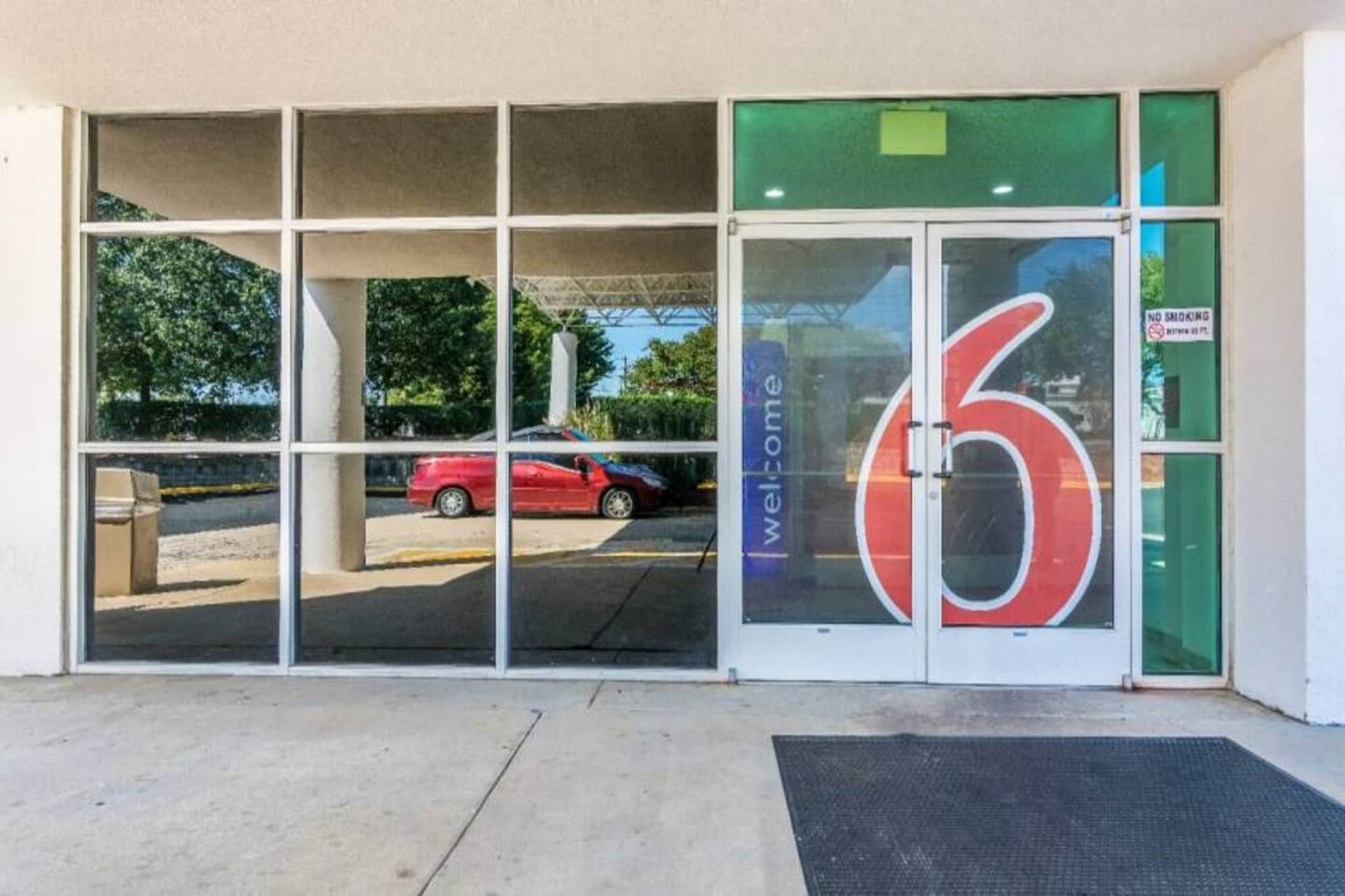 A building entrance with a large glass door featuring a red number '6' and a welcome sign.