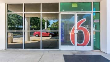 A building entrance with a large glass door featuring a red number '6' and a welcome sign.