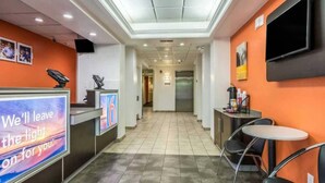 Vestíbulo de hotel con mostrador de recepción, zona de estar y pasillo que lleva a los ascensores.