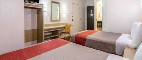 A hotel room with two beds, a desk, a chair, a television, and a wardrobe.