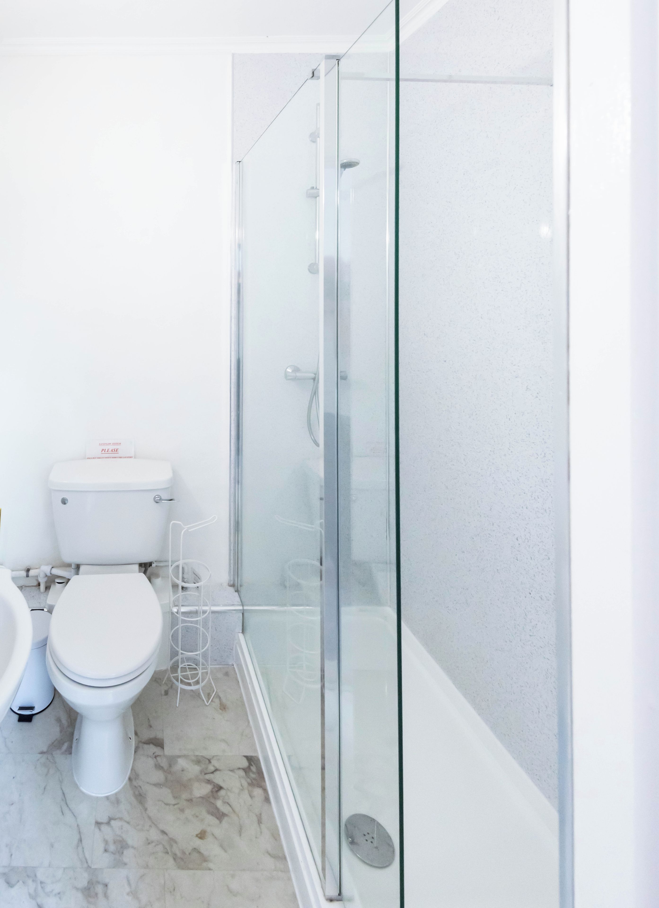 A modern bathroom with a glass-enclosed shower, a toilet, and a bidet.