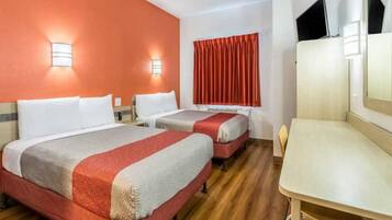 A hotel room with two beds, a desk, and a television.