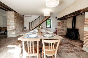A dining area with a wooden table set for four, a staircase, and a brick wall.