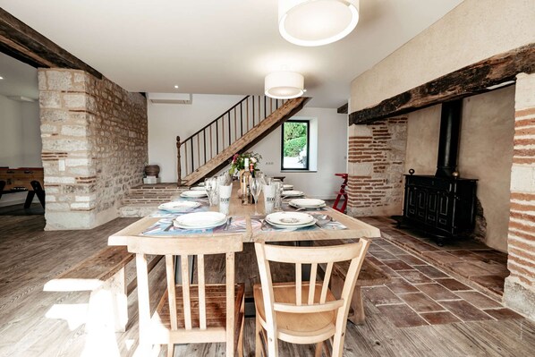 A dining area with a wooden table set for four, a staircase, and a brick wall.