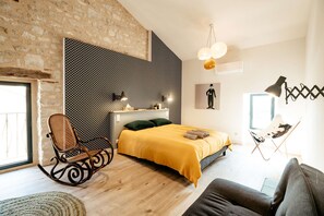 A modern bedroom with a bed, a rocking chair, a sofa, and a wall with a geometric pattern.