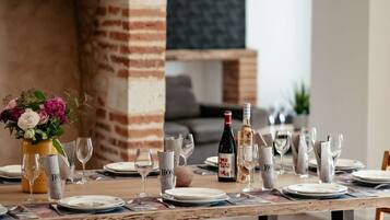 Una tavola imbandita con piatti, bicchieri, posate, una bottiglia di vino e un vaso di fiori.