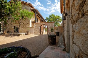 A courtyard with stone buildings, a wooden archway, and potted plants.