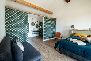 A bedroom with a bed, a chair, a desk, and a bathroom visible through an open door.