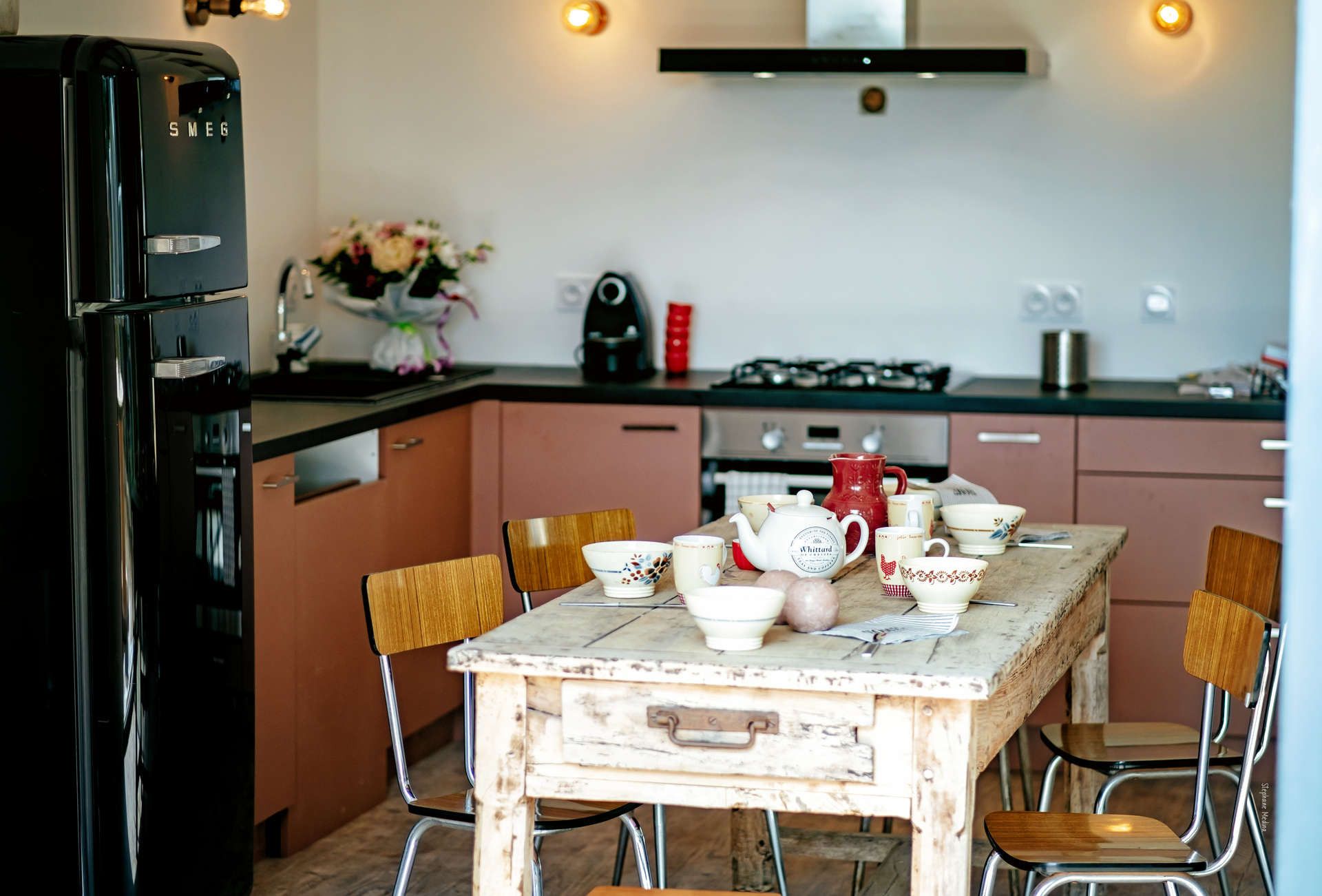 Une cuisine équipée d’une table à manger pour quatre personnes, d’un réfrigérateur, d’une cuisinière à gaz et de divers ustensiles de cuisine.