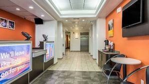 Vestíbulo de hotel con mostrador de recepción, zona de estar y pasillo que lleva a los ascensores.