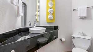 Un baño con lavamanos blanco, inodoro y espejo.