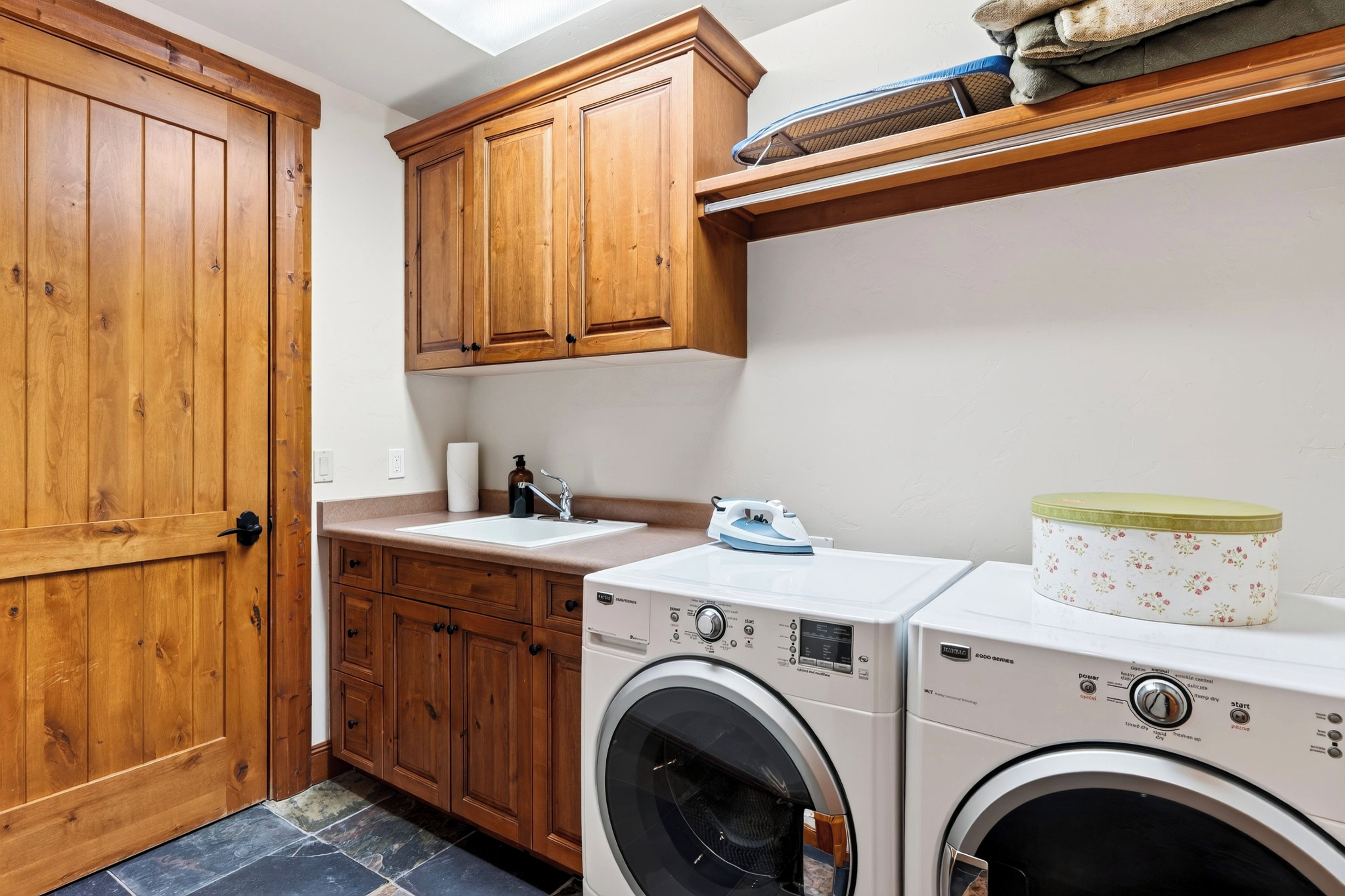 A laundry area with wooden cabinets, a washing machine, and a dryer.