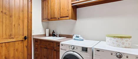 A laundry area with wooden cabinets, a washing machine, and a dryer.
