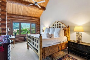 A wooden cabin bedroom with a bed, a desk, and a view of the mountains. - Log Home • Hot Tub + Full Gym | Ski-in/out Funicular | 115 Tristant (Mountain Village)
