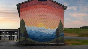 Un edificio con un murale raffigurante un tramonto e montagne.