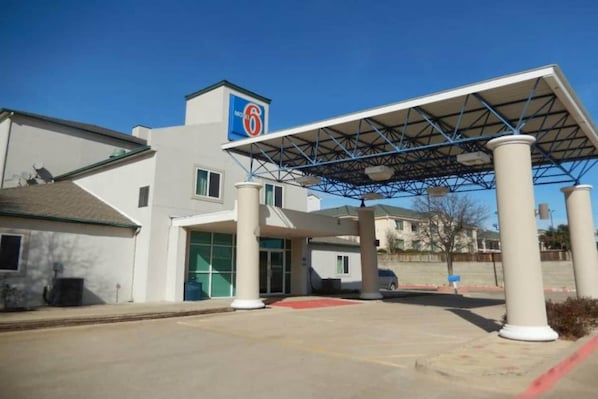 A modern building with a covered entrance, a visible logo, and a clear sky.