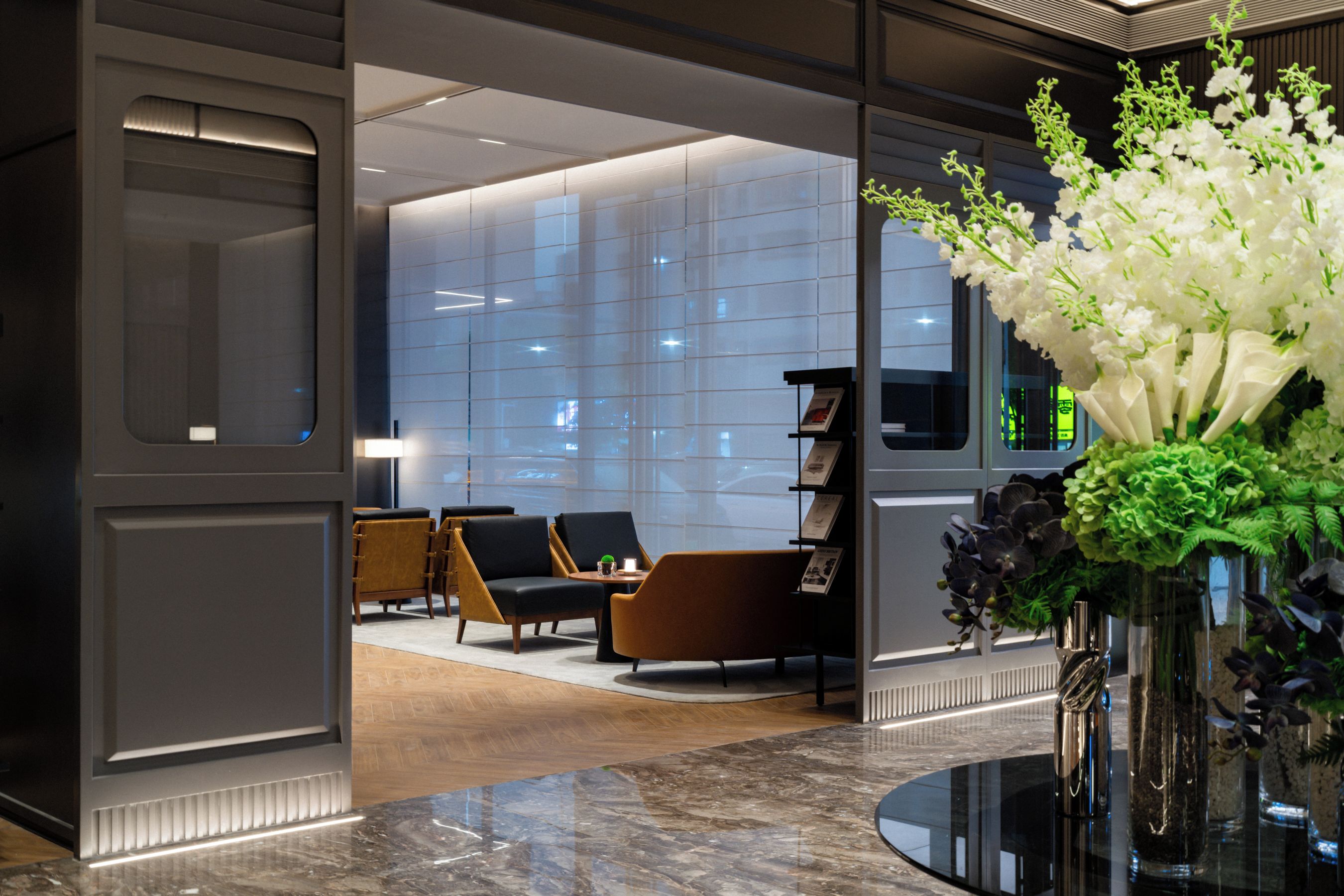A modern lobby with a seating area, a reception desk, and a large window.