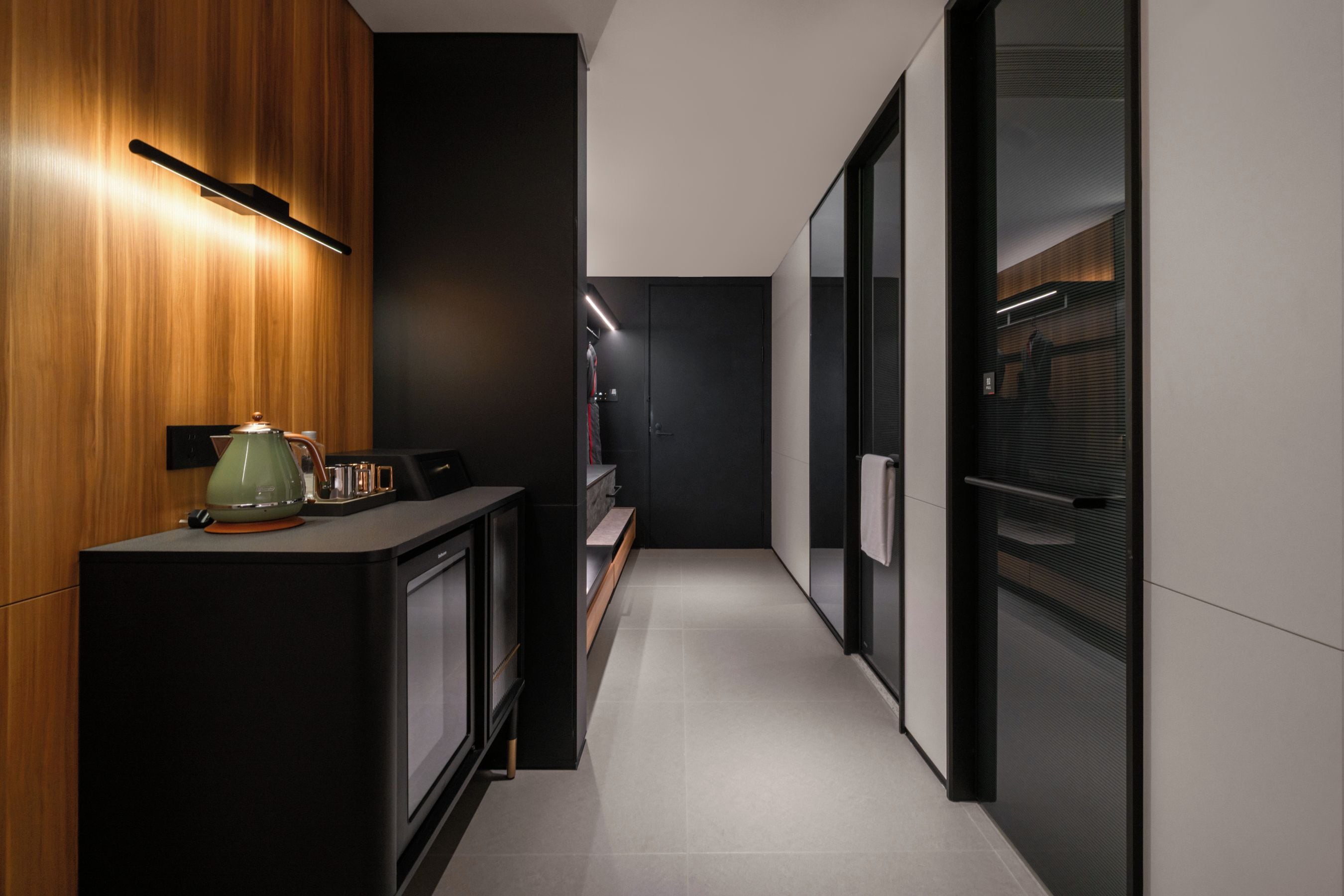 A modern kitchen with a wooden cabinet, a kettle, and a coffee machine.