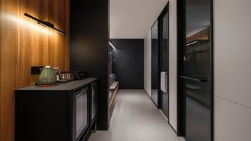 A modern kitchen with a wooden cabinet, a kettle, and a coffee machine.