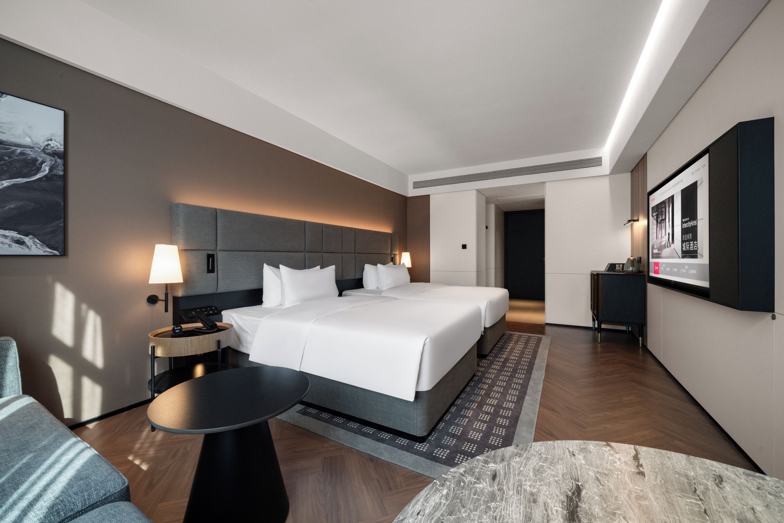 A modern hotel room with a large bed, bedside tables, a desk, and a flat-screen TV.