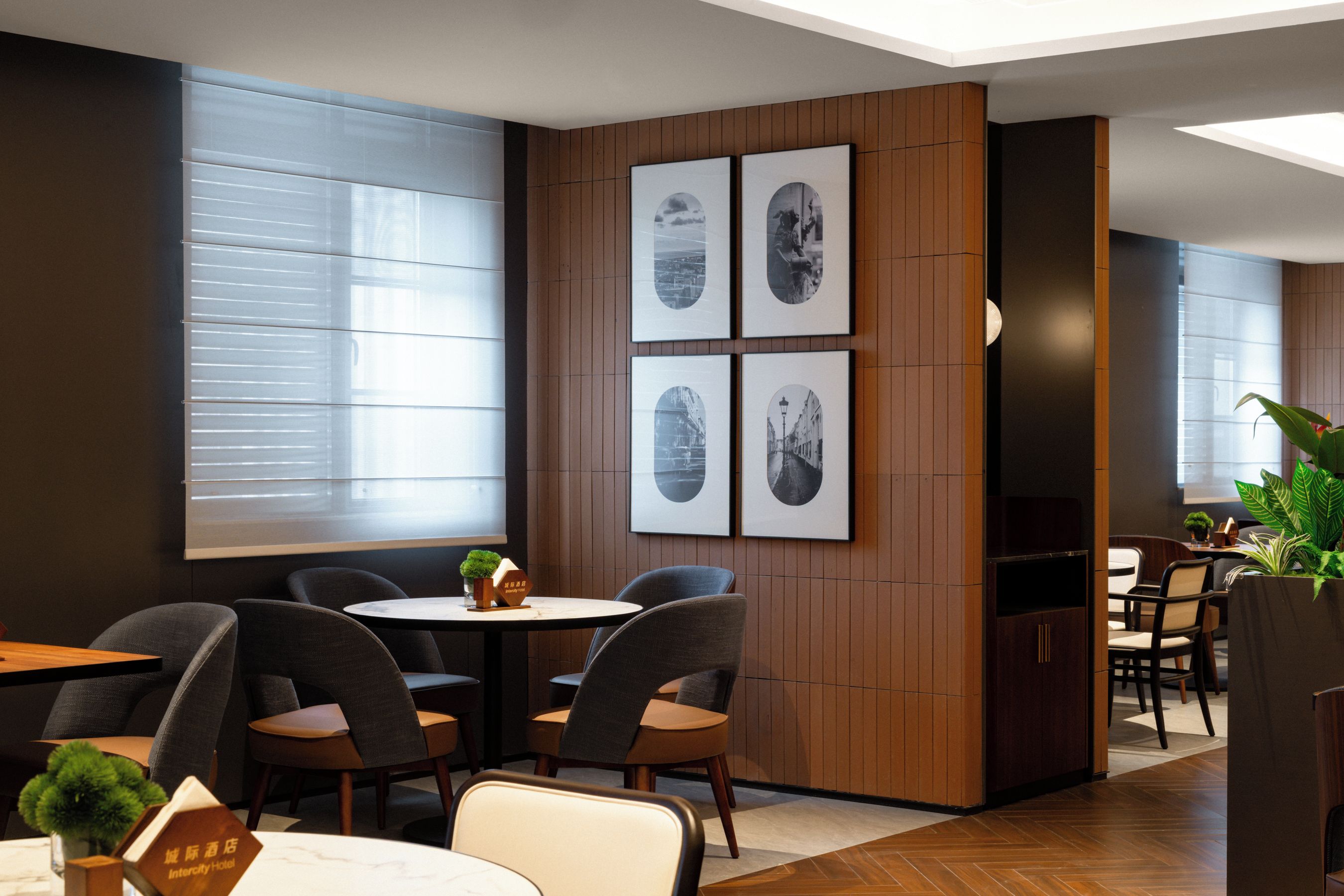 A modern hotel room with a wooden accent wall, a round table, and four chairs.