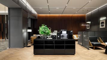 Uma área de recepção moderna com um balcão central, assentos e um canto de café.