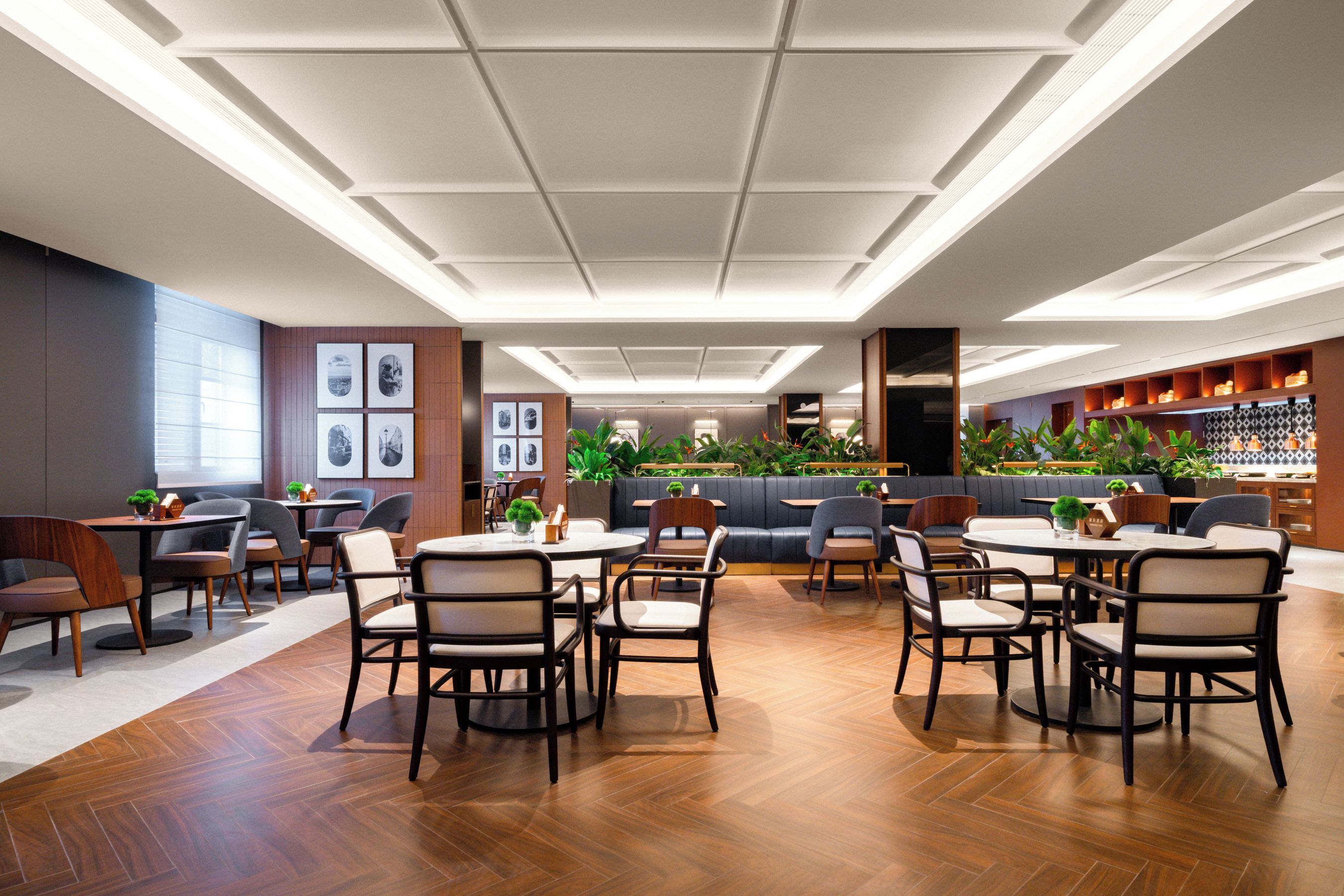 A modern restaurant interior with wooden flooring, round tables, and chairs.