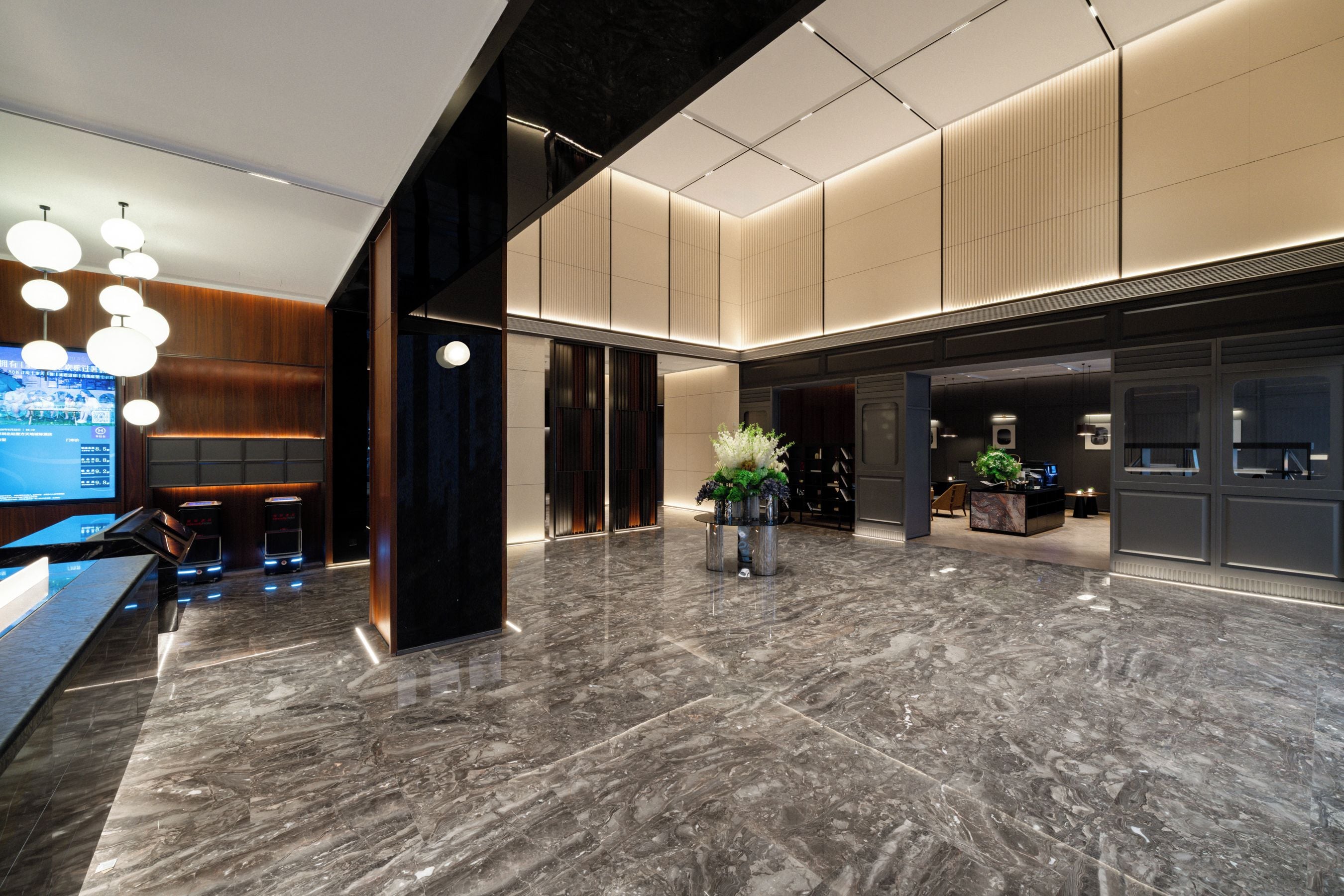 A modern lobby with a marble floor, a reception desk, and a seating area with wooden accents.