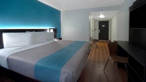 Una habitación de hotel con una cama grande, un escritorio, una silla y un televisor.