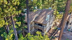 A multi-story building surrounded by dense pine trees. - Forest Views + Pool + Pickleball Access | Near Lake + Ski | Tahoe Pines Retreat (Kings Beach)