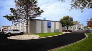 A building with a sign indicating it is a motel, surrounded by parked cars and a grassy area.