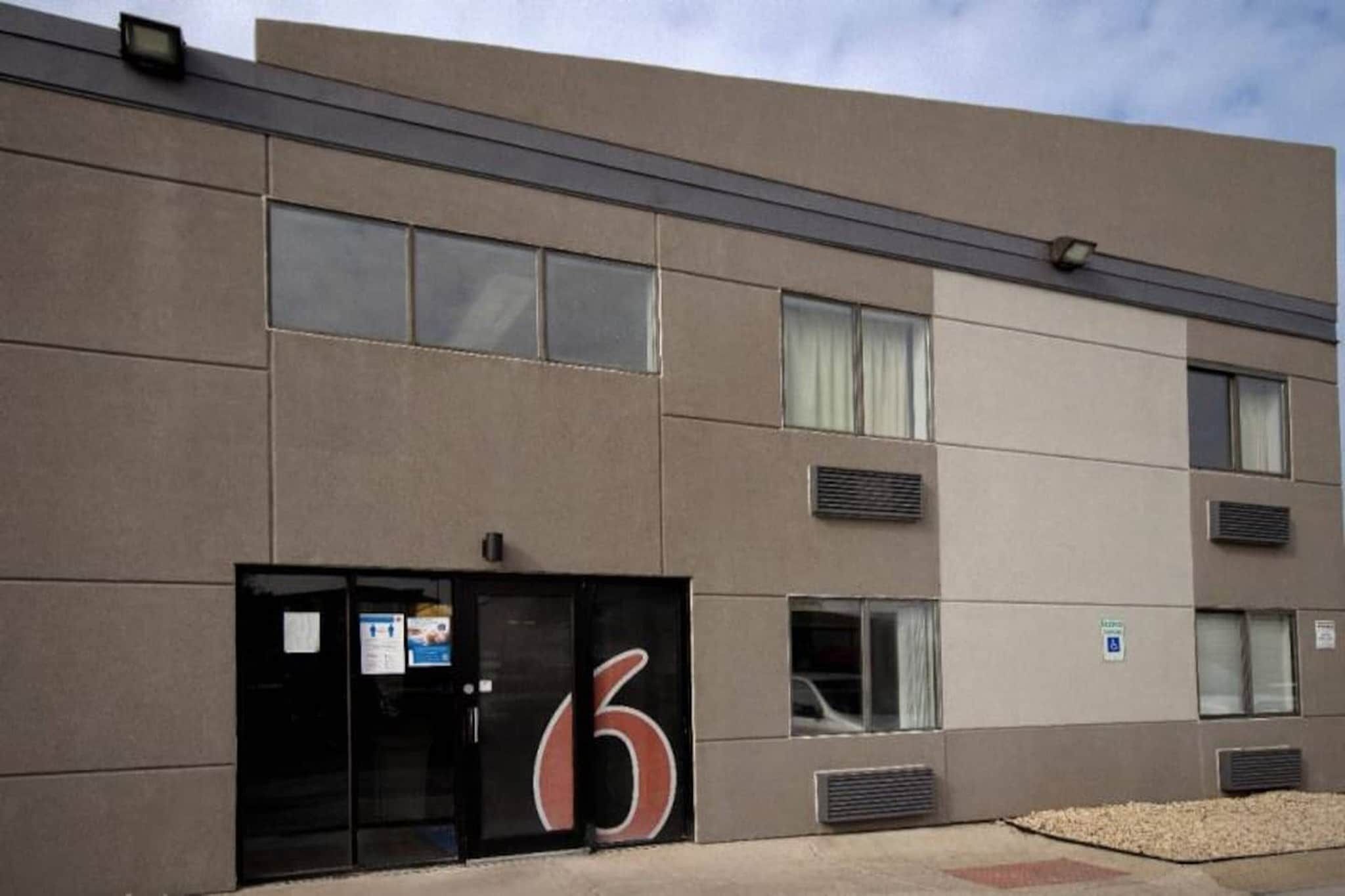 A modern building with a large number '6' sign, multiple windows, and air conditioning units.