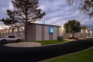 A building with a sign indicating it is a 6-star hotel, surrounded by a parking lot with several vehicles. - 1 Full Bed | ADA/RI Shower (MERRILLVILLE)