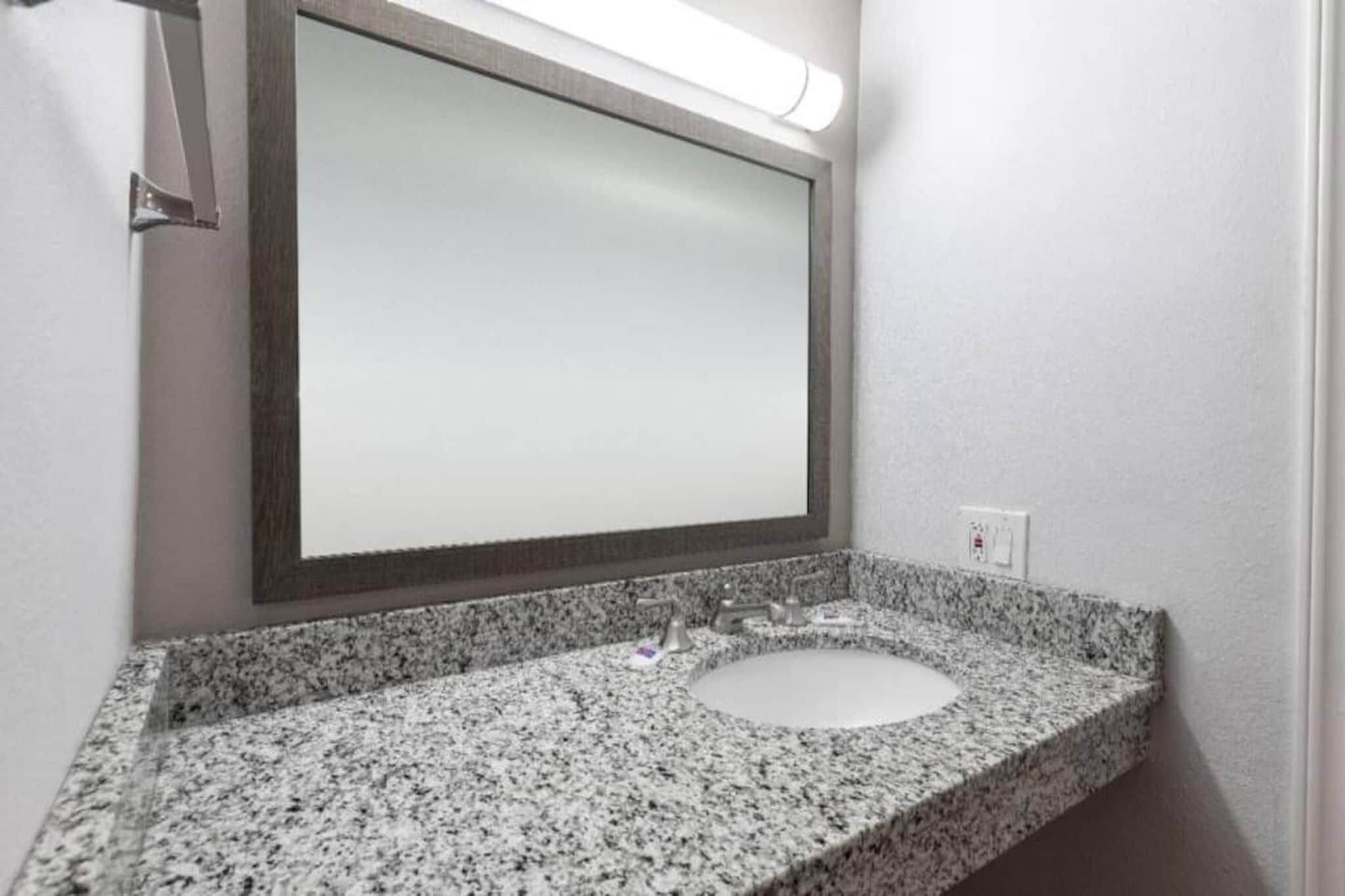 Un bagno con un piano in granito, un lavabo e uno specchio.