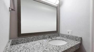 Un bagno con un piano in granito, un lavabo e uno specchio.