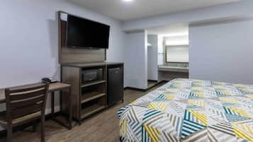 Une chambre d’hôtel comprenant un lit, un bureau avec une chaise, une télévision et un petit réfrigérateur.