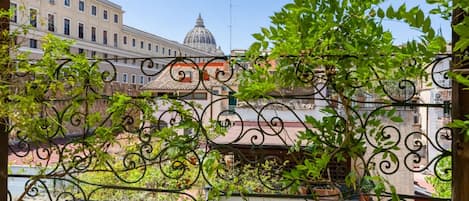 Un balcon orné de balustrades en fer forgé, une vue sur les immeubles et un ciel dégagé.