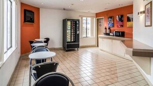A cafe with multiple tables and chairs, a vending machine, and a counter with a coffee machine. - 1 Queen Bed | Smoking (Harvey)