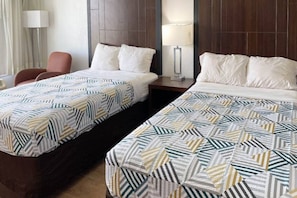 Ein Hotelzimmer mit zwei Einzelbetten, einem Sessel, einem Nachttisch und einer Lampe.