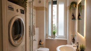 Un bagno moderno con lavatrice, bidet e un ampio lavandino.