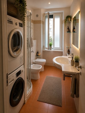 A modern bathroom with a washing machine, bidet, and a large sink. - Salotto San Giovanni (Roma)