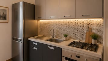Una cocina moderna con un refrigerador de acero inoxidable, una estufa a gas y un lavamanos.