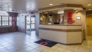A hotel reception area with a reception desk, a clock, and an exit door. - Bright Queen Bed | Non-Smoking (Albuquerque NM)
