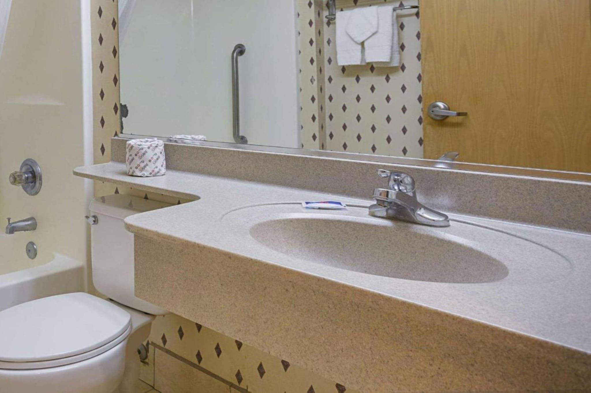 A bathroom with a sink, toilet, and mirror.