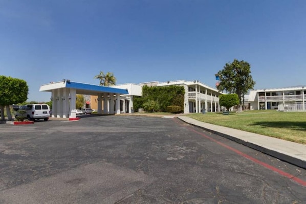 A parking lot with a gas station and a building with multiple floors and balconies. - 1 King Bed | Non-Smoking (Claremont)