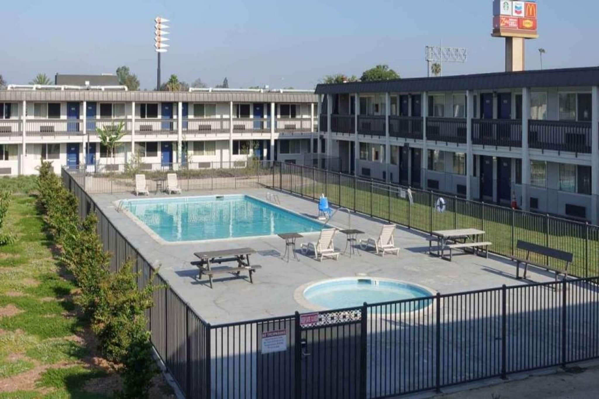 A hotel with a swimming pool, outdoor seating, and a fenced area.