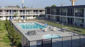 A hotel with a swimming pool, outdoor seating, and a fenced area.