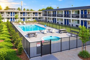A hotel with a swimming pool, outdoor seating, and a fenced area. - 1 King Bed | Non-Smoking (Claremont)