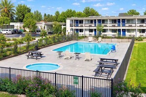 A swimming pool with lounge chairs and a picnic table, surrounded by a fence and greenery. - 1 King Bed | Non-Smoking (Claremont)