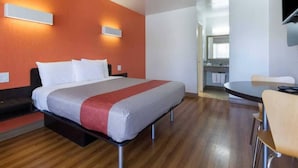 Ett hotellrum med en säng, ett skrivbord och en stol. Man kan se badrummet genom en öppen dörr.